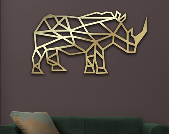 Może przedstawiać: Złota geometryczna rzeźba nosorożca na ścianie wisząca na ciemnoszarej ścianie nad ciemnozieloną sofą z jasnobrązową drewnianą ramą. Sofa ma jasnobrązową poduszkę. Lampa stojąca z szarym abażurem znajduje się w rogu pokoju. Tekst "Matte Gold" znajduje się na dole obrazu.