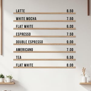 May include: A coffee shop interior with a menu board listing coffee drinks and prices. Baristas are preparing orders behind a wooden counter. The menu includes Latte, White Mocha, Flat White, Espresso, Double Espresso, Americano, and Tea.
