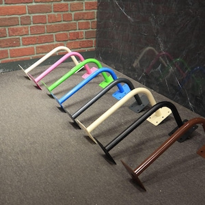 May include: A collection of colorful, curved metal brackets. The brackets are painted in various colors, including pink, green, blue, black, and brown. Each bracket has a flat base for mounting.