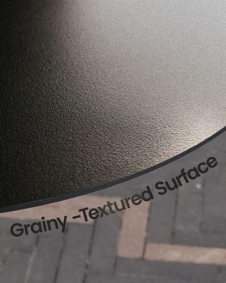 May include: Close-up of a grainy, textured surface. The surface is dark gray and appears to be slightly curved. The words "Grainy - Textured Surface" are printed in a dark font.