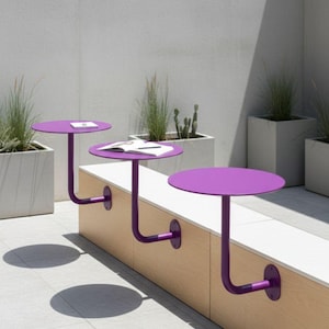 May include: Three purple, round tables attached to a wooden bench. The tables have a curved metal support and are mounted to the bench. The scene is outdoors with potted plants and a light-colored tiled floor.
