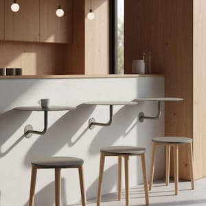 May include: A modern interior with a minimalist design. The image features three wall-mounted, round tables with dark gray tops and curved metal supports. Below, three wooden stools with gray seats and light-colored legs are arranged in a row.