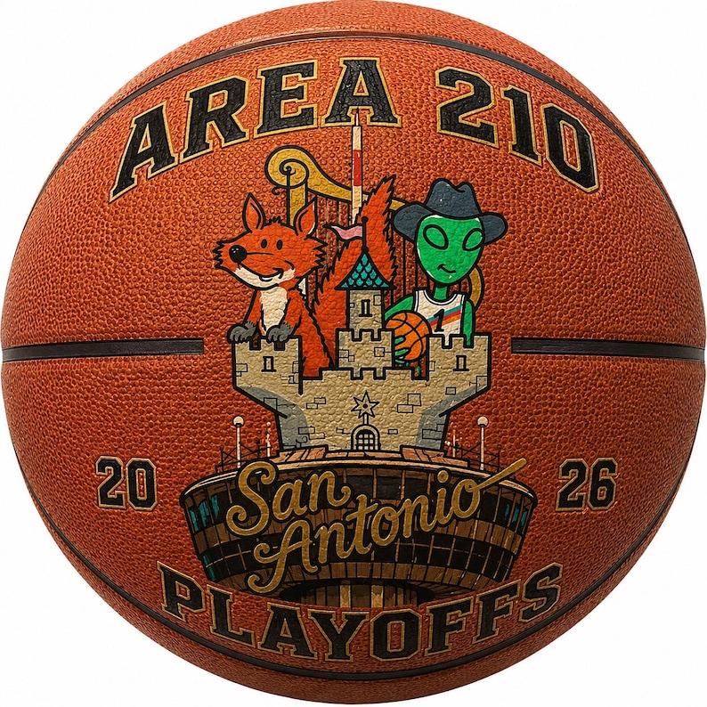 May include: A textured orange basketball featuring the text AREA 210 at the top and 20 26 on the sides. The center graphic depicts a cartoon fox and a green alien wearing a cowboy hat behind a stone castle, with San Antonio PLAYOFFS below.