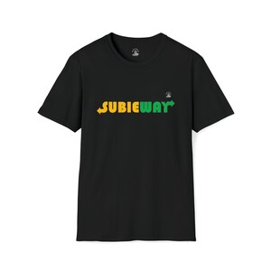 Op de afbeelding: Zwart t-shirt met het woord "SUBIEWAY" in geel en groen, met pijlen. Een klein logo is zichtbaar bij de kraag. Het ontwerp is een parodie op een bekend merk.