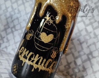 May include: Black tumbler with gold glitter and a honeybee design. The tumbler has the name "Veronica" written in gold glitter on the side.
