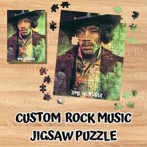 May include: A jigsaw puzzle featuring a portrait of Jimi Hendrix wearing a wide-brimmed hat and a jacket, with the text Jimi Hendrix printed at the bottom. The puzzle is partially assembled, with several loose puzzle pieces scattered around it.