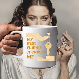 May include: White ceramic mug with the text "MY BEST FRIEND CUCKOLDS ME" in orange letters. The mug features a graphic of a hand holding a key. The mug is held by two people.