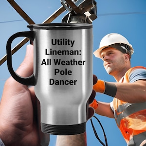 May include: A silver travel mug with a black handle and lid. The mug has the text "Utility Lineman: All Weather Pole Dancer" printed on it.