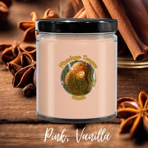 May include: A pink candle in a glass jar with a black lid. The candle has a label with a snail illustration and the words "Flamingo Tongue Snail". The text "Pink, Vanilla" is at the bottom. Cinnamon sticks and star anise are in the background.