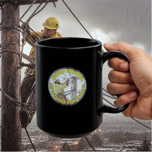 May include: A black ceramic mug featuring a circular graphic of a utility worker on a wooden pole. The text inside the circle reads Utility Lineman All Weather Pole Dancer in yellow lettering. The mug has a smooth finish and a curved handle.