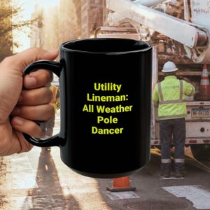 May include: A black ceramic mug featuring yellow text that reads Utility Lineman: All Weather Pole Dancer. The mug has a smooth, glossy finish with a curved handle on the side, designed for holding hot beverages in a standard cylindrical shape.