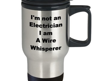 May include: A silver travel mug with a black lid and handle. The mug has the text "I'm not an Electrician I am A Wire Whisperer" printed on it.