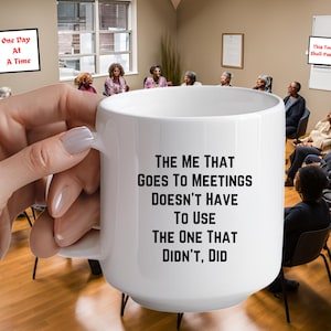 May include: White ceramic coffee mug with a black text design that reads "The me that goes to meetings doesn't have to use the one that didn't, did".