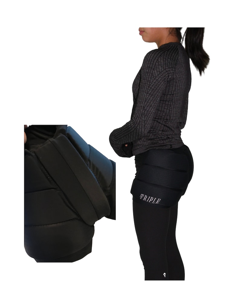May include: Black padded shorts with the word "TRIPLE" printed on the left thigh. The shorts are worn by a person wearing a black long-sleeved shirt.