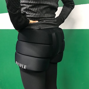 May include: Black padded shorts with a white "TRIPLE" logo on the side. The shorts are designed for protection and comfort.