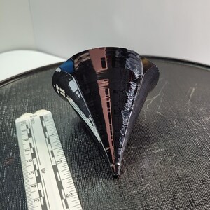 Puede incluir: Objeto negro en forma de cono con acabado brillante. El objeto est&aacute; junto a una regla. El cono mide aproximadamente 10 cm de altura.