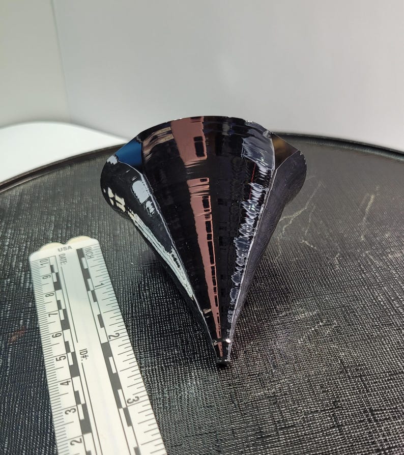 Puede incluir: Objeto negro en forma de cono con acabado brillante. El objeto est&aacute; junto a una regla. El cono mide aproximadamente 10 cm de altura.