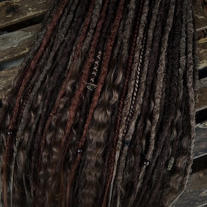 Può includere: Un set di dreadlock sintetiche marroni, castano rossiccio e bionde con perline. Le dreadlock sono disposte in fila e sono pronte per essere installate.