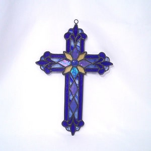 May include: A stained glass cross with a blue and purple design and a yellow flower in the centre.