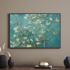May include: A framed painting of a blooming almond tree with white blossoms against a blue sky. The painting is in a black frame and is hanging on a light brown wall.