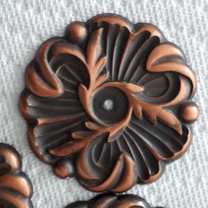 Peut inclure: Une pièce d'accent décorative en métal avec un motif floral. La pièce est de forme ovale et a une finition brun foncé avec des accents cuivre.