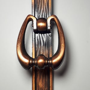 May include: A decorative door knocker with a copper finish and a black and copper patterned backplate.