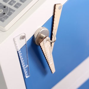 Pu&ograve; includere: Primo piano di una superficie metallica blu con tre righelli attaccati ad essa mediante magneti. I righelli sono in legno, plastica e metallo. I righelli sono di dimensioni diverse e hanno diverse marcature.