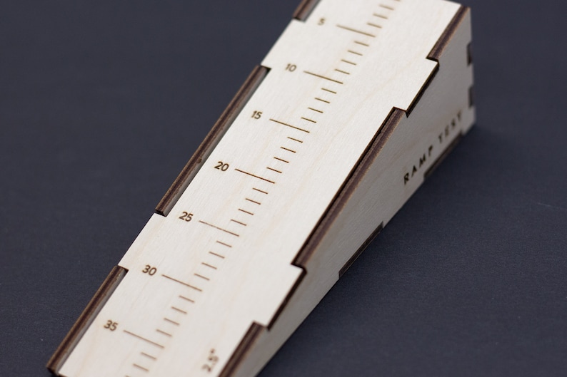 May include: A wooden ramp with a ruler marked in inches from 5 to 40. The ramp is labeled "RAMP TEST" on the side.