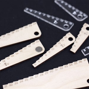 Pu&ograve; includere: Un set di cinque righelli in legno con diverse scale di misura. I righelli sono contrassegnati da numeri da 1 a 37. I righelli hanno un piccolo foro a un'estremit&agrave; e un disco di metallo all'altra estremit&agrave;.