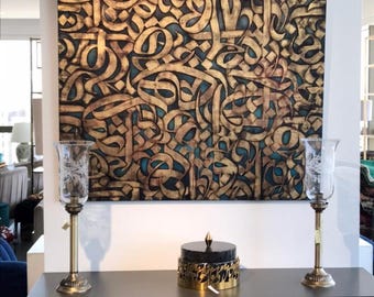 Könnte beinhalten: Eine goldene und schwarze Dekobox mit aufwendigen Kalligrafie-Designs steht auf einer dunkelgrauen Kommode mit zwei goldenen Kerzenständern. Die Box steht auf einem schwarzen Sockel und hat einen goldenen Deckel mit einer spitzen Spitze.