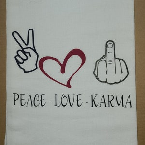 Puede incluir: Toalla de cocina blanca con un signo de paz negro, un corazón rojo y un dedo medio negro. El texto "Peace - Love - Karma" está impreso debajo de los símbolos.