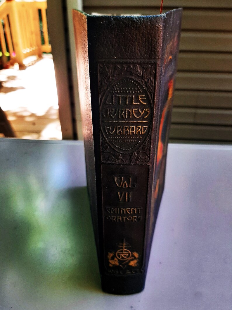 May include: A dark brown leather-bound book titled "Little Journeys" by Hubbard. The book is part of a series titled "Eminent Orators" and is volume VII.