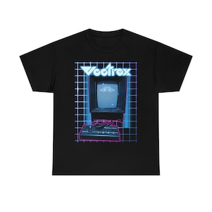 May include: Black t-shirt with a retro-style graphic of a vintage computer with the text "Vectrex" on the screen. The computer is surrounded by a blue and pink grid pattern.