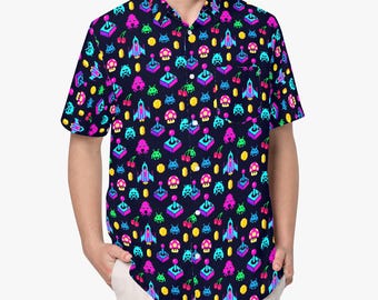 Pode incluir: Uma camisa de manga curta com botões em azul-marinho escuro, apresentando uma estampa neon de elementos de videojogos retro, incluindo joysticks pixelizados, naves espaciais, cogumelos, cerejas e moedas de ouro. A camisa tem um colarinho padrão.