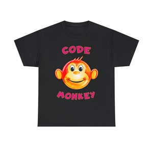 Puede incluir: Camiseta negra con un gráfico rosa "CODE MONKEY". El gráfico presenta una cara de mono de dibujos animados con un esquema de color amarillo y naranja.