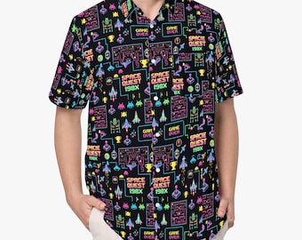 Pode incluir: Uma camisa preta de manga curta com botões, apresentando um padrão vibrante e repetitivo de elementos de jogos arcade retro, incluindo naves espaciais pixelizadas, labirintos, troféus dourados, joysticks e o texto "SPACE QUEST 198X" e "GAME OVER".