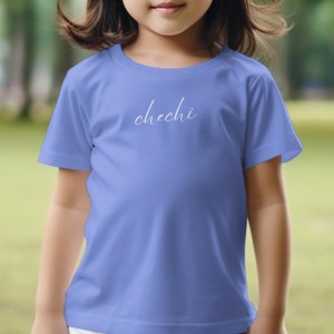Könnte beinhalten: Ein hellblaues T-Shirt mit dem Wort "chechi" in Weiß auf der Vorderseite.
