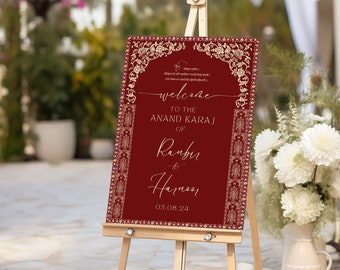 Può includere: Un cartello di benvenuto rosso con accenti dorati e bordi decorati. Il cartello recita "Benvenuti all'Anand Karaj di Ranbir & Harnoor 03.08.24".