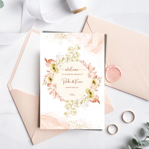 May include: A wedding ceremony welcome sign with a floral wreath design in shades of peach, green, and gold. The text reads "Welcome to the wedding ceremony of Ranbir & Kiara January 03rd, 2021".