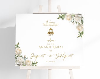 May include: White wedding welcome sign with gold text and floral accents. The sign reads "Welcome to the Anand Karaj of Jagpreet & Sukhpreet 05.25.2024".
