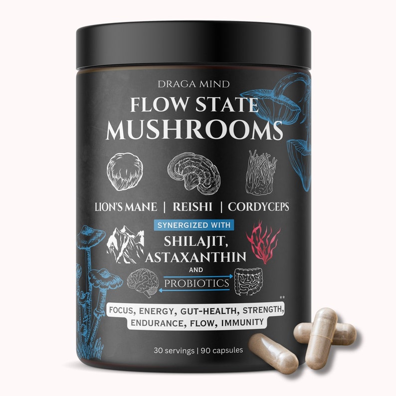 May include: Black bottle with a white label that reads "DRAGA MIND FLOW STATE MUSHROOMS" with illustrations of mushrooms and the text "LION'S MANE | REISHI | CORDYCEPS" and "SYNERGIZED WITH SHILAJIT, ASTAXANTHIN AND PROBIOTICS". The label also includes the text "FOCUS, ENERGY, GUT-HEALTH, STRENGTH, ENDURANCE, FLOW, IMMUNITY" and "30 servings | 90 capsules". Three brown capsules are in the foreground.
