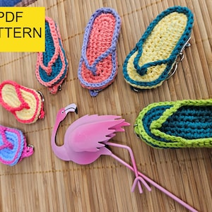 Puede incluir: Una colección de chanclas de ganchillo hechas a mano y un adorno de flamenco rosa. Las chanclas son de varios colores, incluyendo rosa, azul, amarillo y verde. El texto "PDF PATTERN" está en un recuadro amarillo.