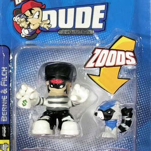 Puede incluir: Un monopatín Tech Deck Dude Evolution con Bernie & Filch, una figura de rayas blancas y negras con una máscara negra, sosteniendo un billete de dólar, y una figura Zoods azul y blanca. El monopatín es rojo con ruedas negras y el embalaje es azul con las palabras "Tech Deck" y "Dude Evolution" en blanco.