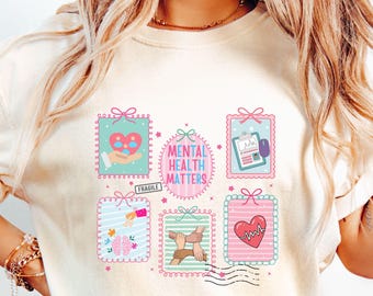 May include: Cream-colored sweatshirt featuring a colorful graphic design with the text "MENTAL HEALTH MATTERS." The design includes various illustrations within decorative frames, such as a heart, hands, and brain, in shades of pink, blue, and green.