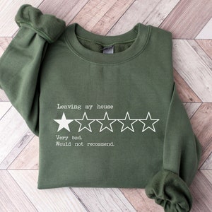 May include: A green sweatshirt with a white graphic that says "Leaving my house" and has a one-star rating with the text "Very bad. Would not recommend."