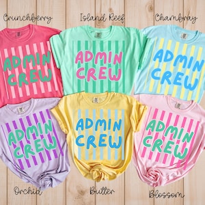 May include: A collection of six short-sleeved crew neck t-shirts in various pastel colors including pink, mint green, light blue, lavender, yellow, and light pink, each featuring vertical stripes and the text ADMIN CREW printed in bold letters.