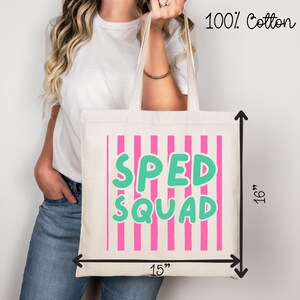 May include: A cream-colored tote bag made of 100% cotton featuring vertical pink stripes and the text SPED SQUAD in large teal letters. The bag measures 15 inches in width and 16 inches in height as indicated by the black measurement arrows.