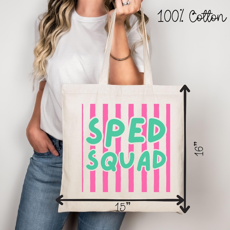 May include: A cream-colored tote bag made of 100% cotton featuring vertical pink stripes and the text SPED SQUAD in large teal letters. The bag measures 15 inches in width and 16 inches in height as indicated by the black measurement arrows.