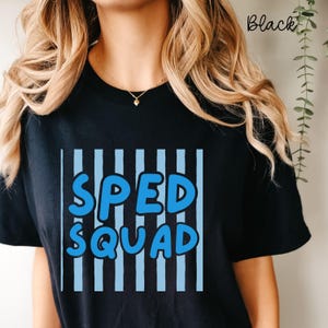 May include: A black short-sleeved t-shirt featuring a graphic design with vertical light blue stripes and the text "SPED SQUAD" in bold, rounded blue letters. The shirt has a crew neckline and a solid black background color throughout.