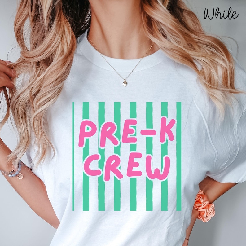 May include: White t-shirt featuring the text "PRE-K CREW" in pink letters with a white outline, set against vertical green stripes. The word "White" is printed in the upper right corner.